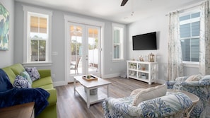 Relax in this open-plan living space featuring a green sofa, coffee table, and flat-screen TV.