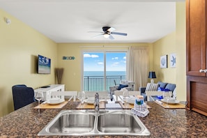 A kitchen with a large window, a ceiling fan, and a view of the ocean.