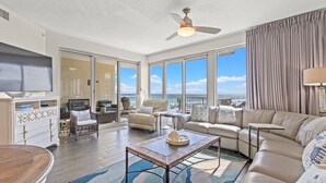 A spacious living area with a large window overlooking a scenic view, a ceiling fan, and a cozy seating arrangement. - Crescent at Miramar-gulf Front Luxury Condo-free Beach Chairs! (Miramar Beach)