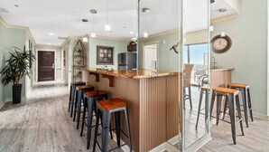 A kitchen with a bar area, wooden bar stools, and a large mirror.