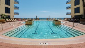 A swimming pool with a 3 1/2 ft depth limit and no diving sign, surrounded by lounge chairs and a view of the ocean.