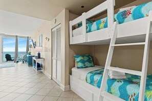 A room with bunk beds, a desk, and a view of the ocean. - Beautiful 5th Floor Aqua Resort Unit With Direct Ocean Views, Sleeps 8! (Panama City Beach)