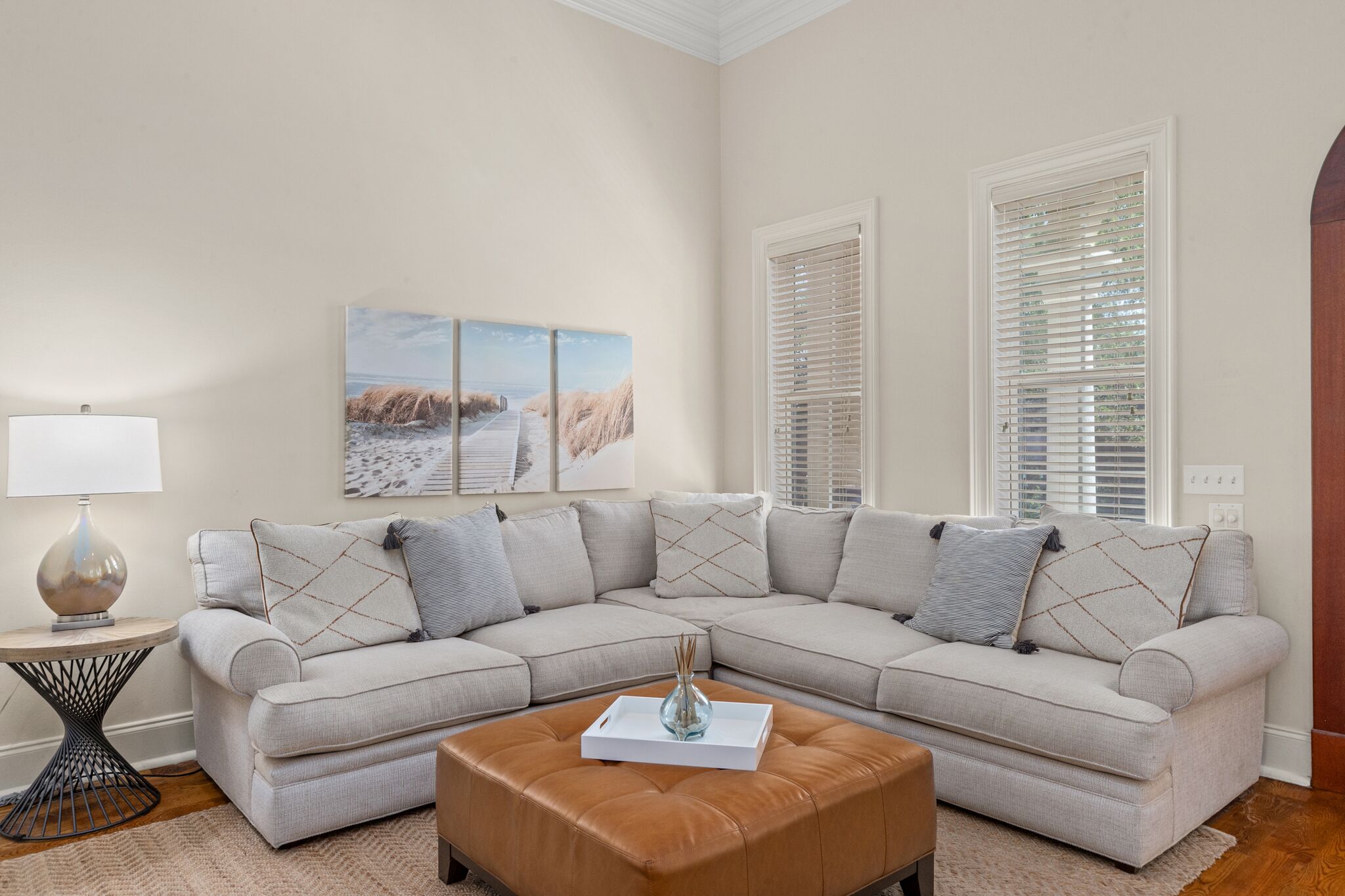 A living room with a sectional sofa, a coffee table, a lamp, and artwork on the wall.
