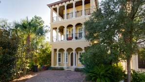 A two-story building with a balcony on the upper floor, surrounded by greenery. - Luxury Home Steps From Beach in Gated Community (Santa Rosa Beach)