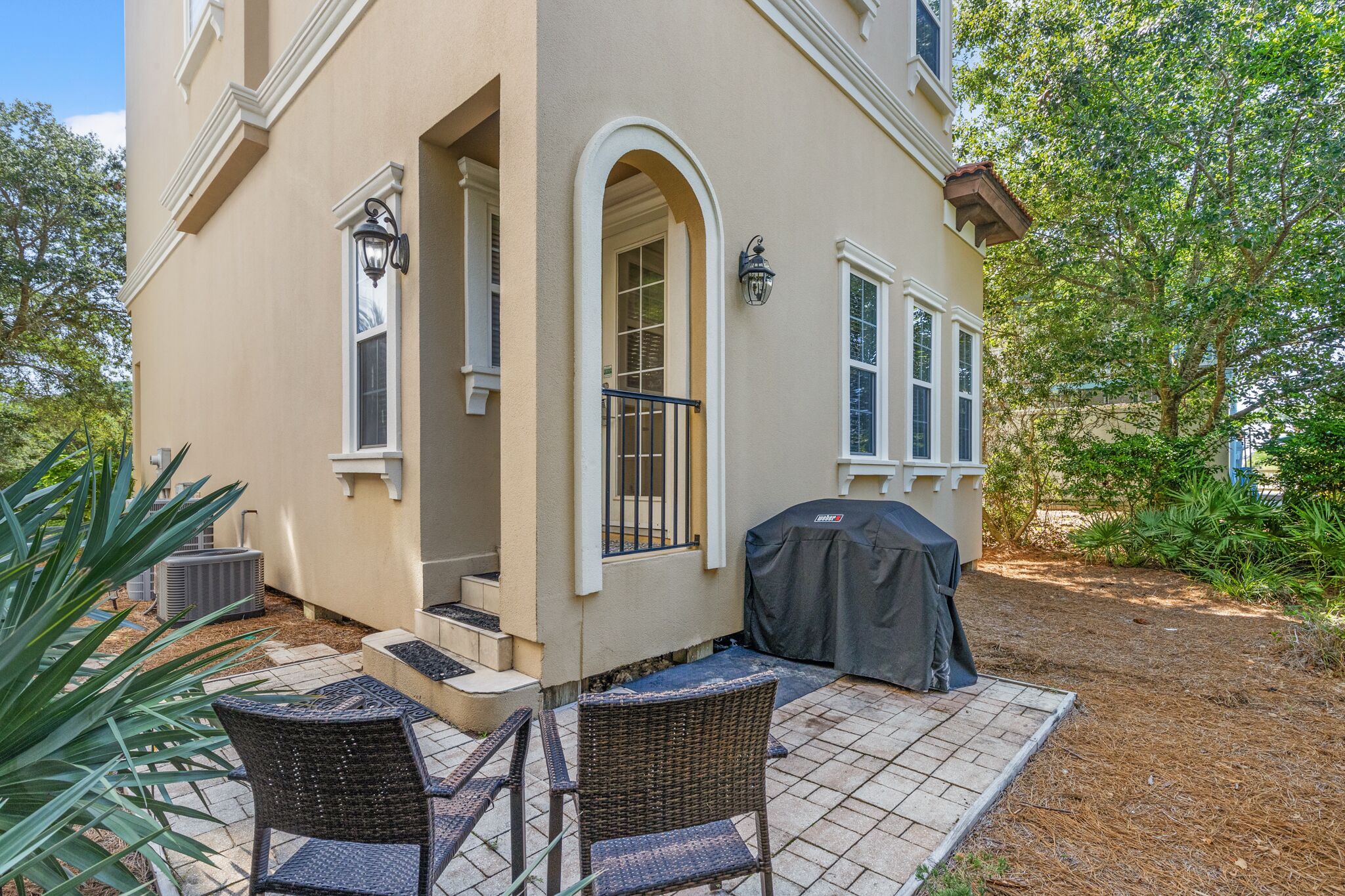 A house with a patio area featuring wicker furniture and a barbecue grill.