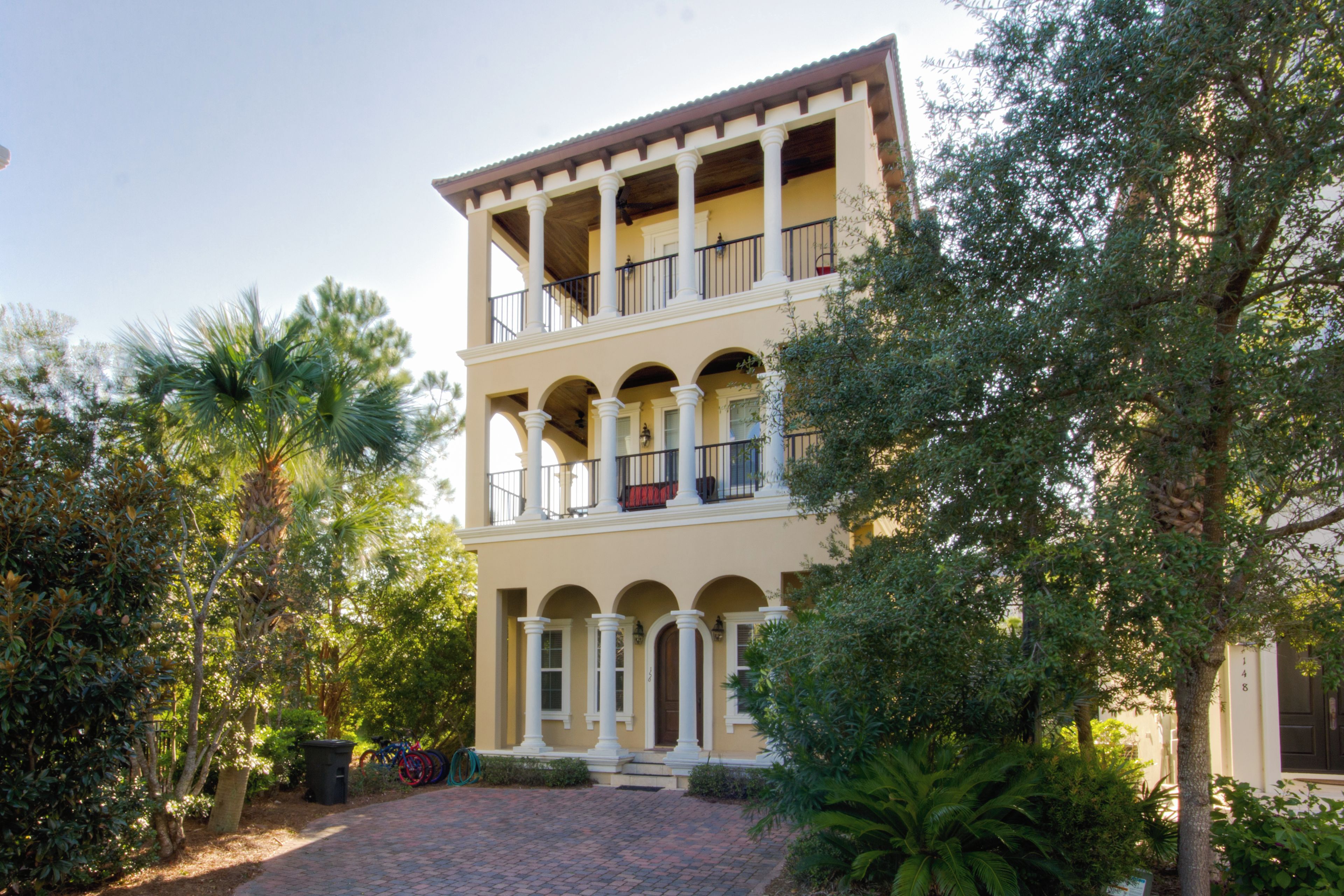 A two-story building with a balcony on the upper floor, surrounded by greenery.