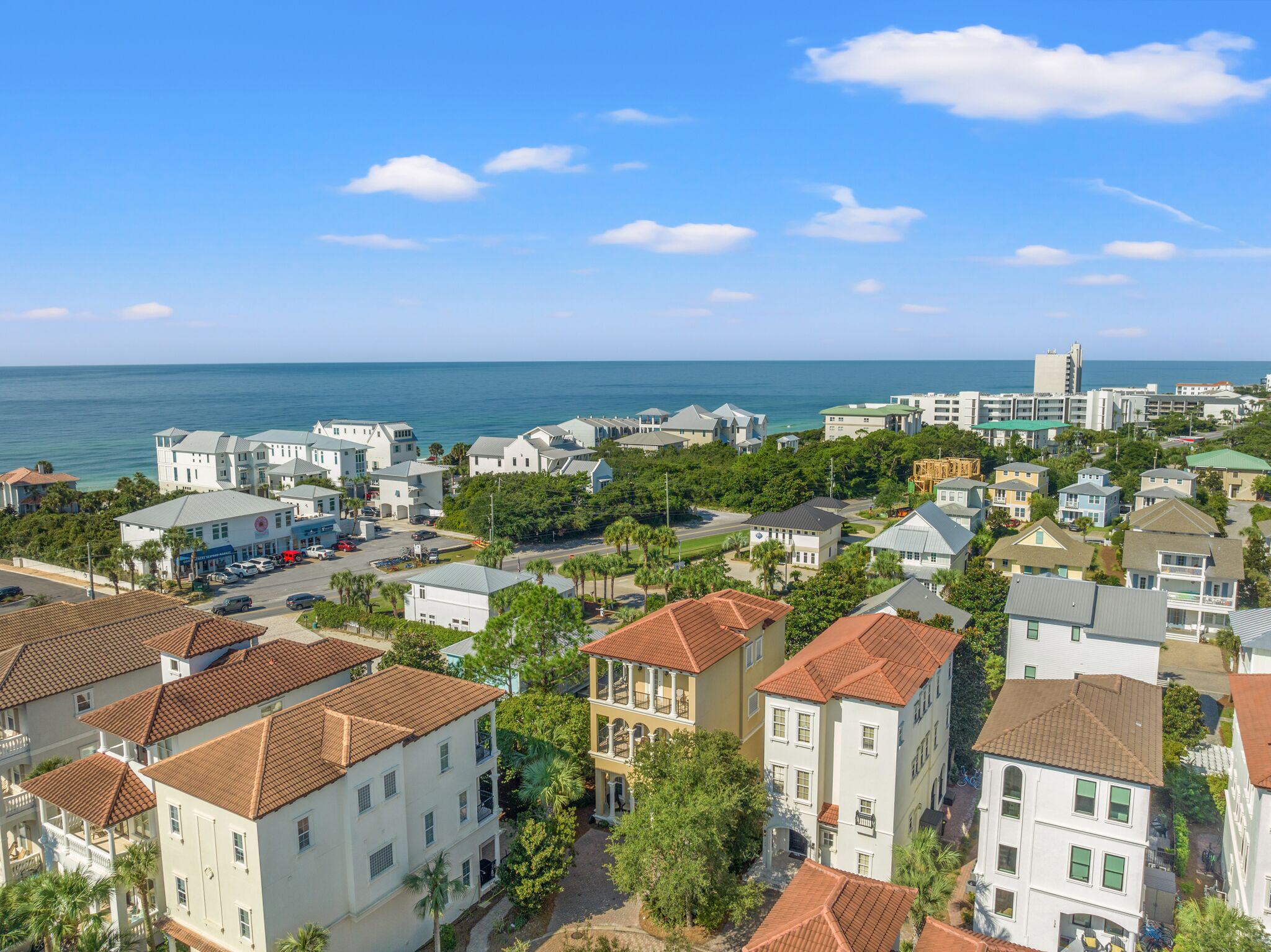 A coastal residential area with a mix of single and multi-story buildings, some with red-tiled roofs and others with flat designs.