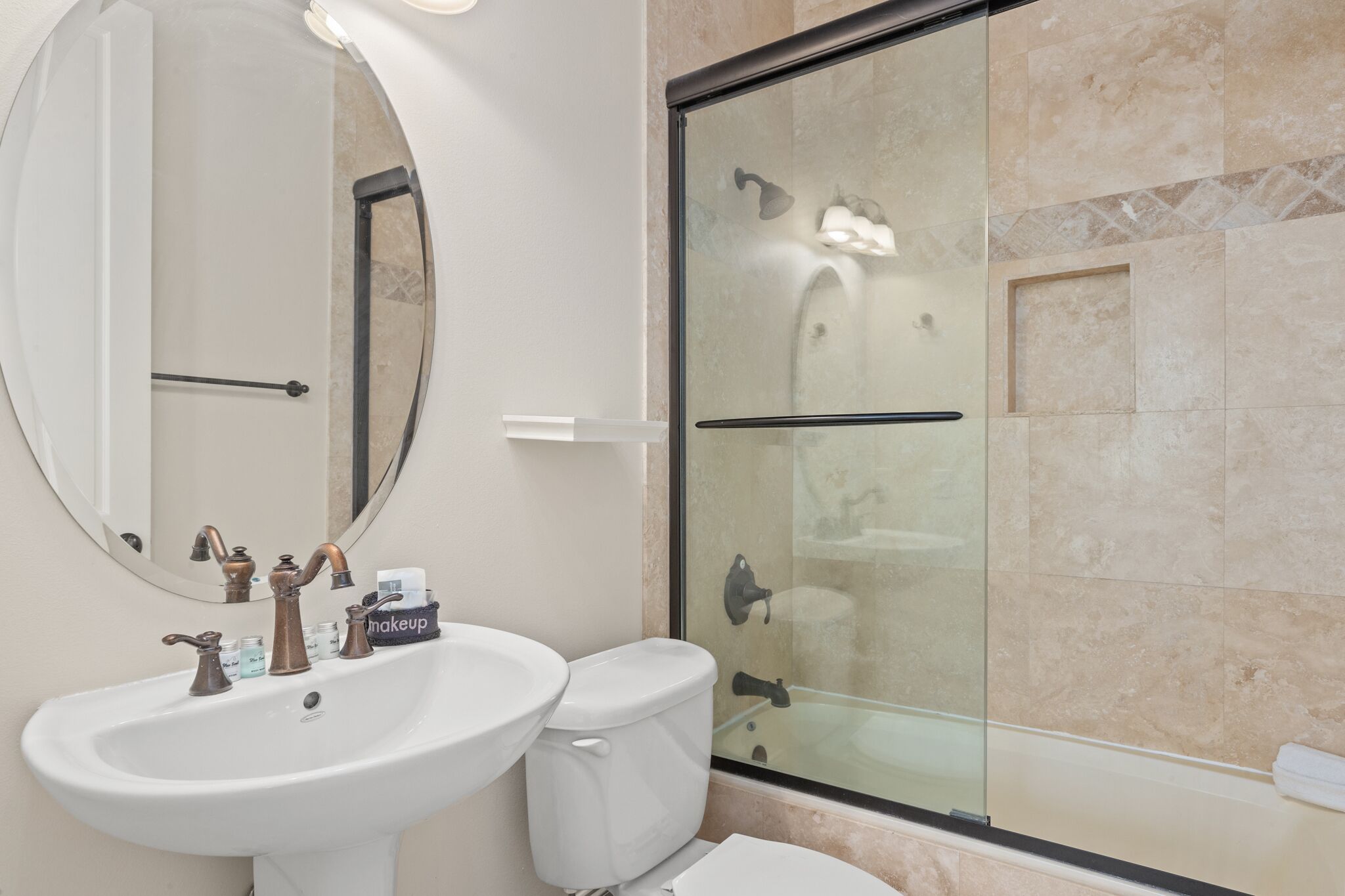 A bathroom with a white sink, a toilet, a glass-enclosed shower, and a large mirror.
