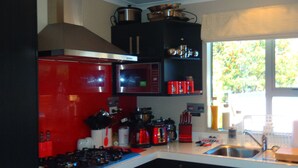 Een keuken met een rode kookplaat, zwarte kastjes en een magnetron.