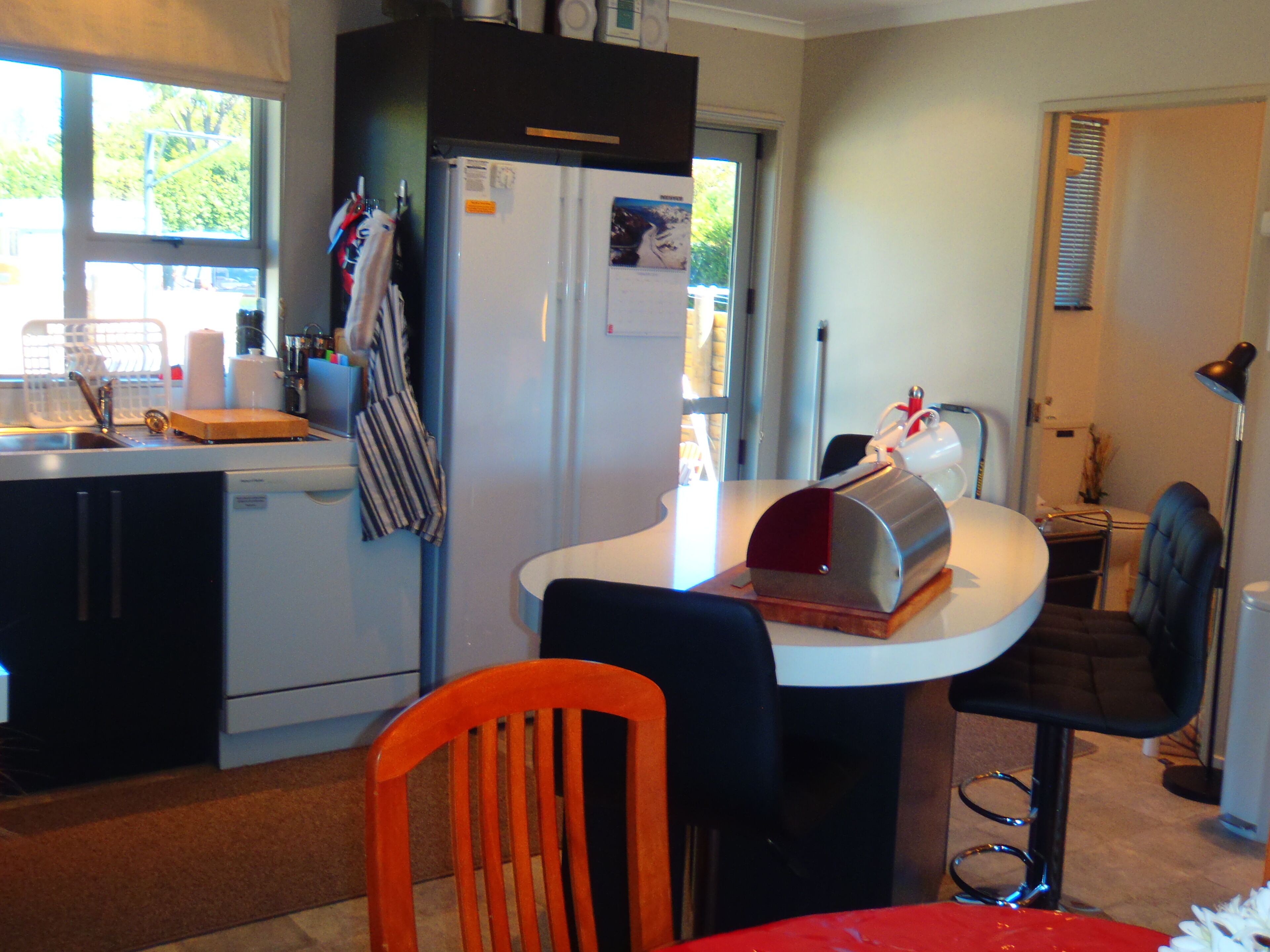 A compact kitchen with a refrigerator, sink, and a small dining area with a chair and table.