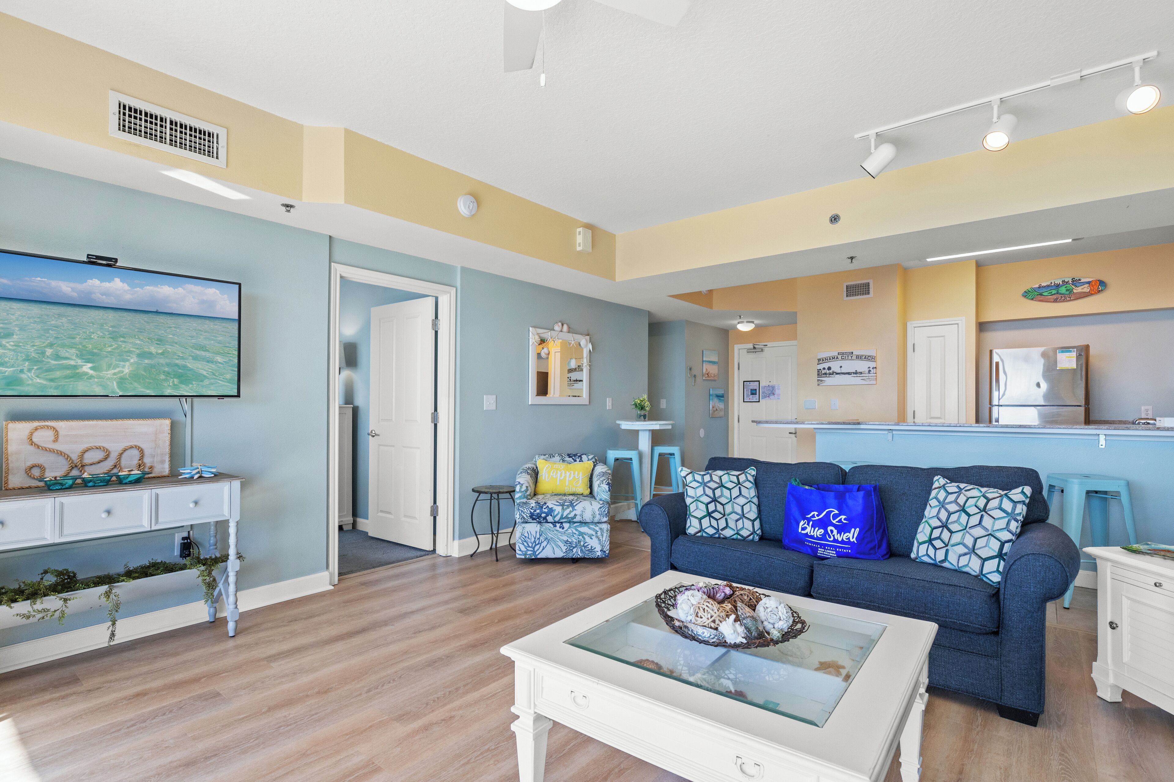 A living room with a blue sofa, a white coffee table, and a flat-screen TV.