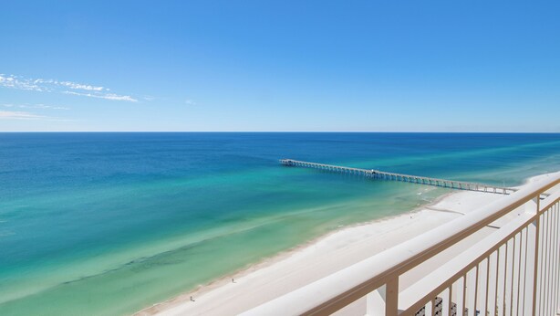 A beach with clear turquoise water, a sandy shore, and a pier extending into the sea. - Penthouse! Beautiful Views! Newly Remodeled and Listed! (Panama City Beach)