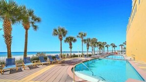 A poolside area with lounge chairs and palm trees, overlooking a clear blue sky and ocean. - Penthouse! Beautiful Views! Newly Remodeled and Listed! (Panama City Beach)