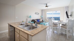 A kitchen with granite countertops, a dishwasher, and a dining area with a white table and chairs. - Penthouse! Beautiful Views! Newly Remodeled and Listed! (Panama City Beach)
