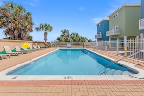A swimming pool with a 3 FT depth marker, surrounded by a white fence, palm trees, and a building with balconies. - Next To Pier Park! Steps From the Beach! Dog-friendly! Pool! (Panama City Beach)