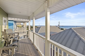 A covered balcony with a view of the ocean and neighboring buildings. - Next To Pier Park! Steps From the Beach! Dog-friendly! Pool! (Panama City Beach)