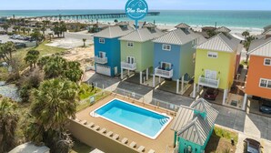 Une propriété située en bord de mer, avec des maisons aux couleurs vives, une piscine et une jetée qui s’avance dans l’océan.
