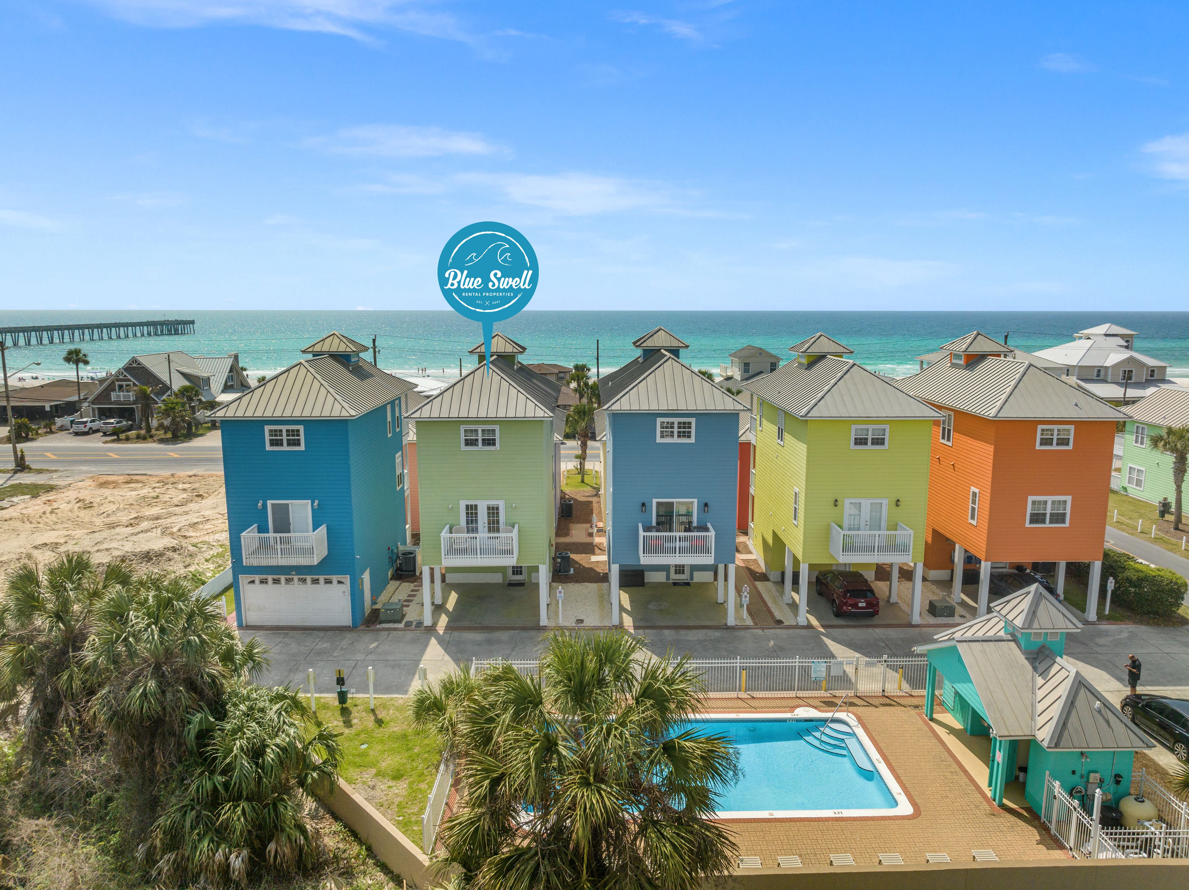 A row of colorful beach houses with a pool, beach access, and ocean views.