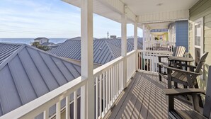 Un balcon abrité avec des balustrades blanches, une table et des chaises.