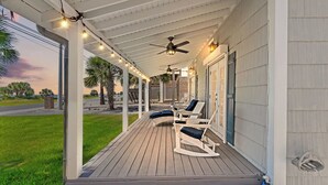 A covered porch with a ceiling fan, string lights, and outdoor seating. - Cute Beach Cottage Steps to the Beach! Panama City Beach, FL! (Panama City Beach)