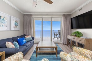 Relax in this stylish living room with a sofa, coffee table, and armchair, offering a view of the ocean.