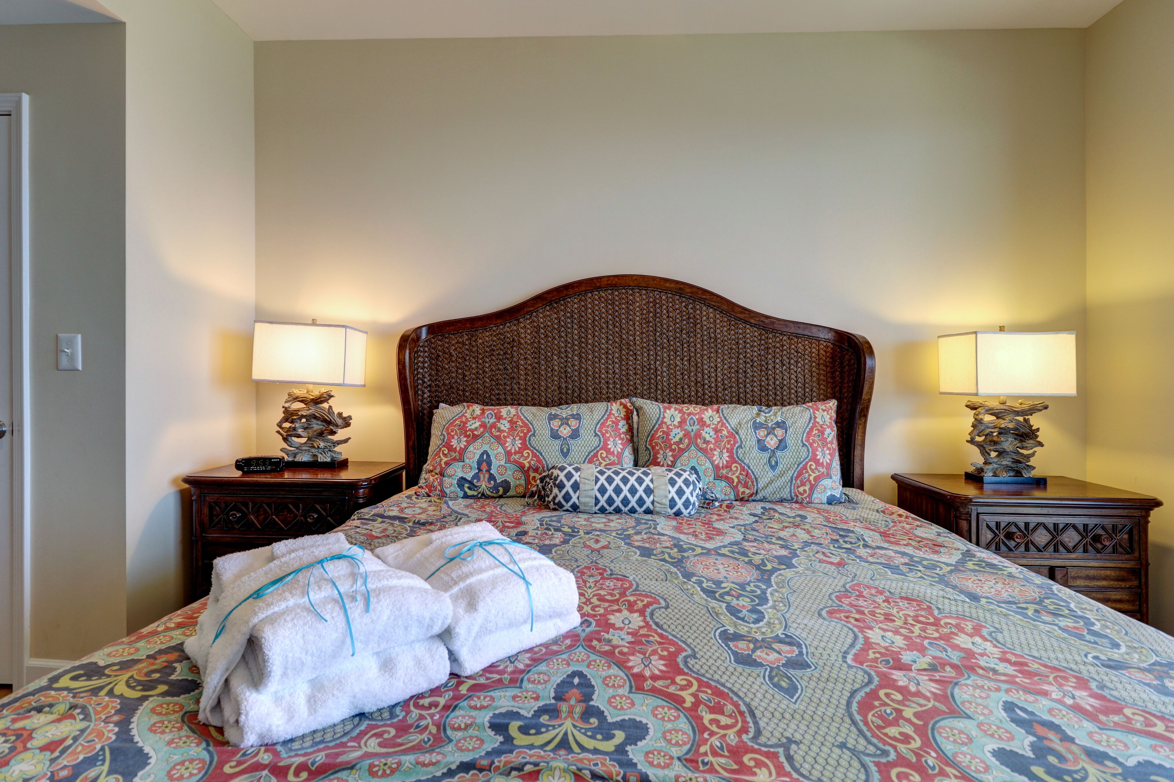 A neatly made bed with patterned bedding, two bedside lamps, and a decorative headboard.