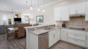 A modern kitchen with white cabinetry, granite countertops, and a built-in dishwasher.