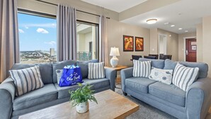 A modern living room with two grey sofas, a coffee table, and a view of the city.