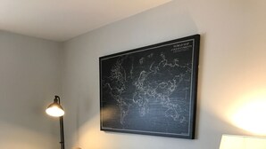 Uma sala de estar moderna com um sofá cinza, manta listrada e um mapa-múndi na parede.