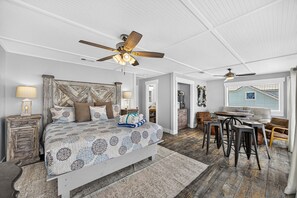 A bedroom with a large bed, a ceiling fan, a desk with chairs, and a view of the outside. - Luxury Gulf Front Property! Directly on the Beach! Sleeps 15! (Panama City Beach)