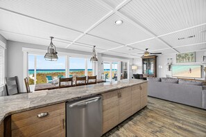 A modern kitchen with a large island, wooden cabinets, and pendant lighting. - Luxury Gulf Front Property! Directly on the Beach! Sleeps 15! (Panama City Beach)