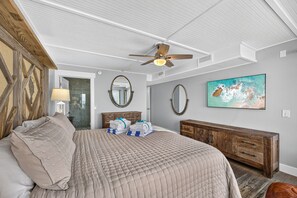A bedroom with a bed, a wooden headboard, a ceiling fan, a large painting, and a wooden dresser. - Luxury Gulf Front Property! Directly on the Beach! Sleeps 15! (Panama City Beach)