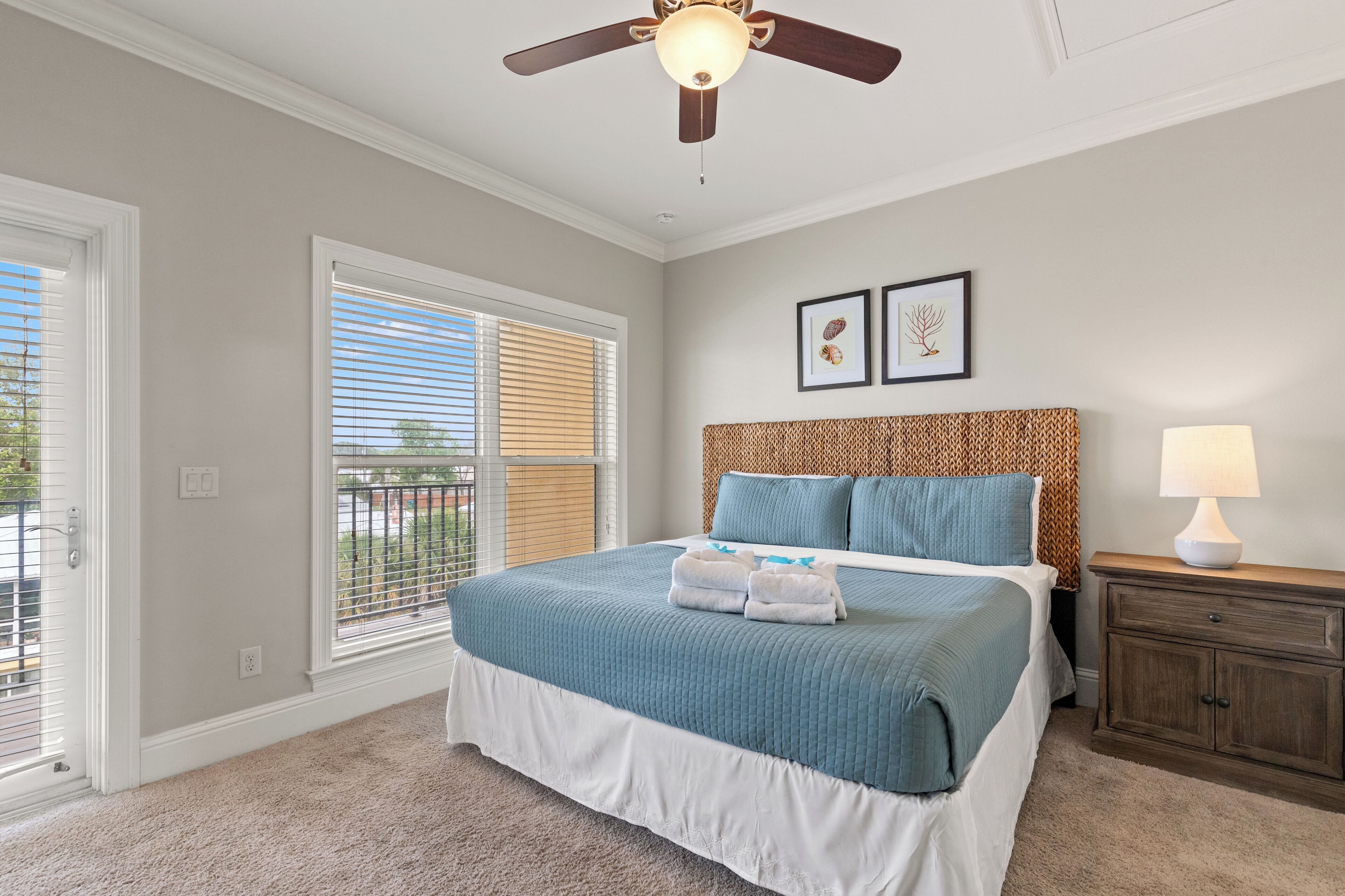 A bedroom with a bed, a ceiling fan, a nightstand, and a window with blinds.