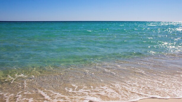 Une plage à l’eau turquoise et limpide, où les vagues sont douces.