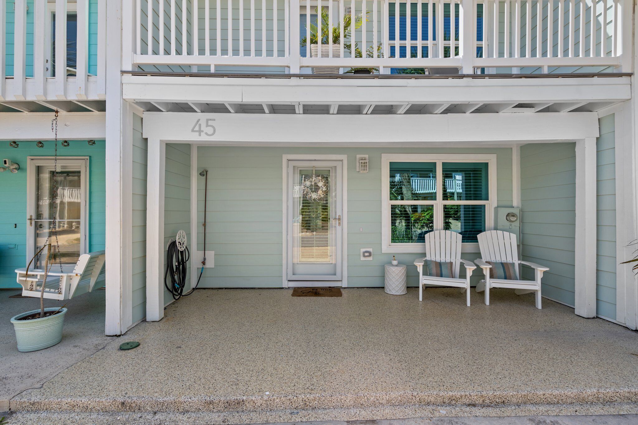 A two-story building with a porch, numbered 45, featuring a door, windows, and outdoor seating.