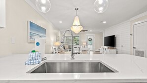Una cucina moderna con un'ampia isola, lavello in acciaio inossidabile e illuminazione a sospensione.