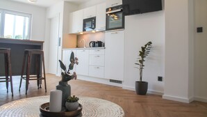 Une cuisine moderne avec des meubles blancs, un four noir et une plante en pot.