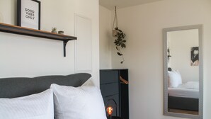 Une chambre à coucher avec un lit, des oreillers, une étagère avec des plantes, un miroir et une cheminée.