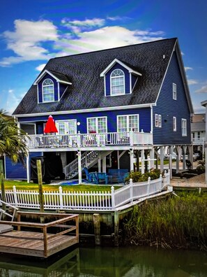 A two-story house with a balcony, a covered porch, and a dock extending into a body of water. - WONDERFUL VACATION OPPORTUNITY, STEPS FROM BEACH, SLEEPS 14 (North Myrtle Beach)