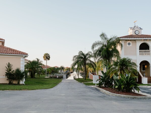 A residential street with houses, palm trees, and a building with a clock tower.