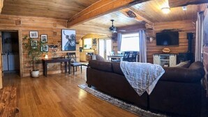 Interior de una cabaña de madera con sala de estar, comedor y cocina.