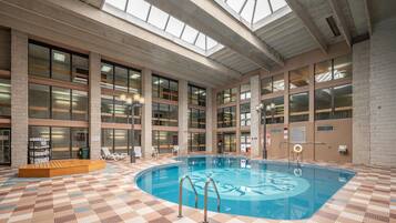 Relax by the oval-shaped pool surrounded by lounge chairs and a wooden platform.