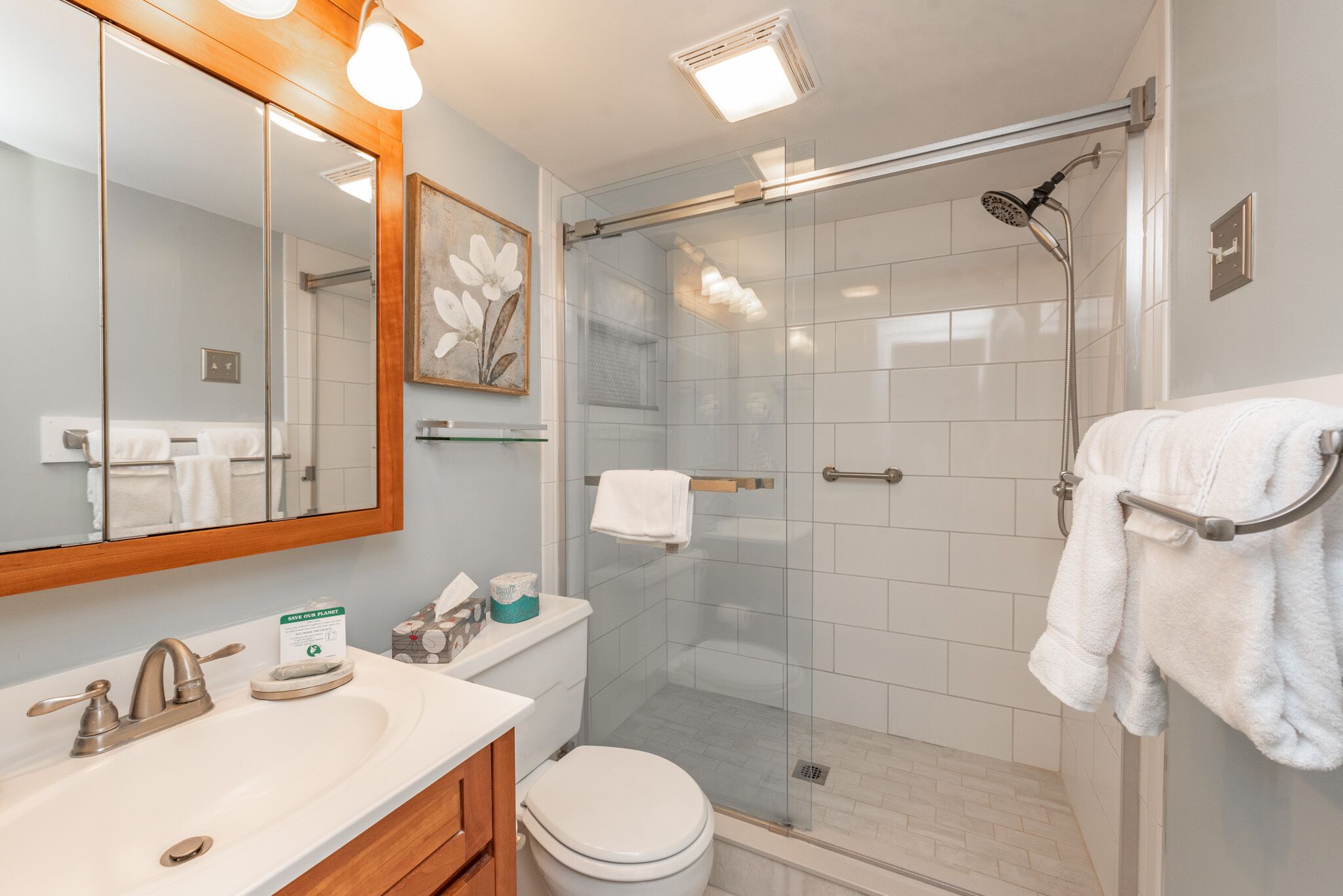Een moderne badkamer met een douchecabine van glas, een wit wastafelmeubel en een toilet.