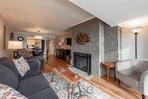 A living room with a fireplace, a sofa, a coffee table, and a lamp.