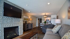 Una sala de estar con chimenea, un sofá, una mesa de centro y un comedor con candelabro.