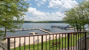 A lakeside view with a dock, boats, and a sandy beach area.