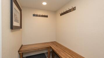 A corner room with a wooden bench, a coat rack, and a framed picture on the wall.