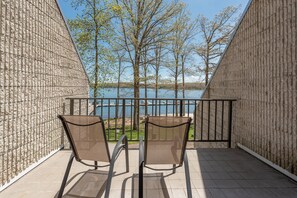 Relax on the balcony with a serene view of the lake and surrounding trees.