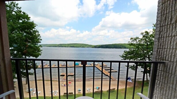 A balcony with a view of a lake, dock, and beach. - Will O' The Wisp: 303D Two Bedroom/Two Bath (Oakland)