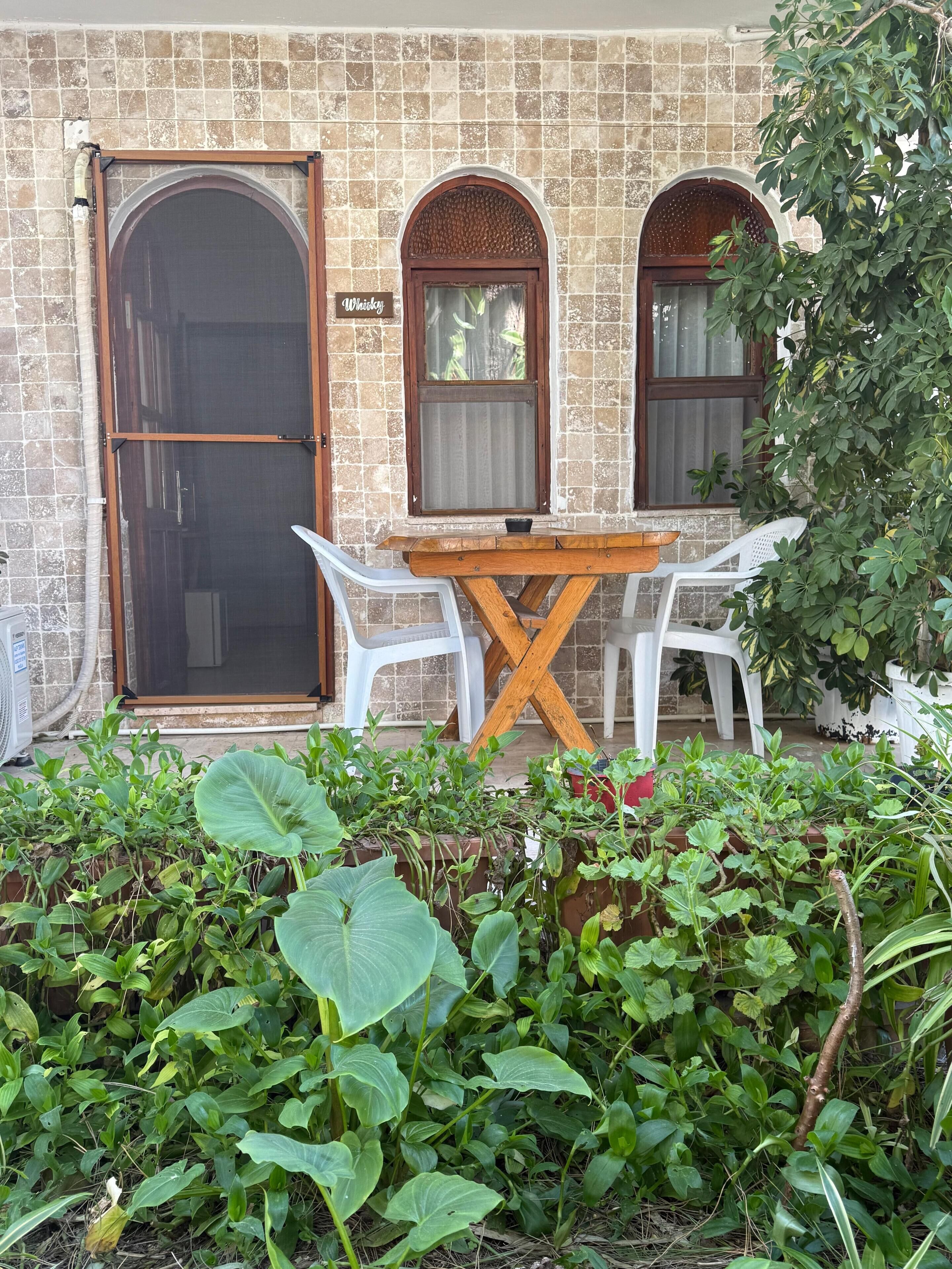 A building with a tiled exterior, a wooden table with chairs, and a sign reading "Whiskey."